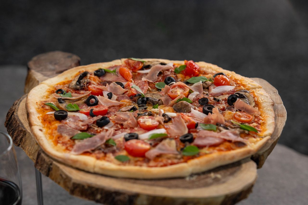 Freshly baked gourmet pizza with toppings on a rustic wooden board, perfect for food lovers.